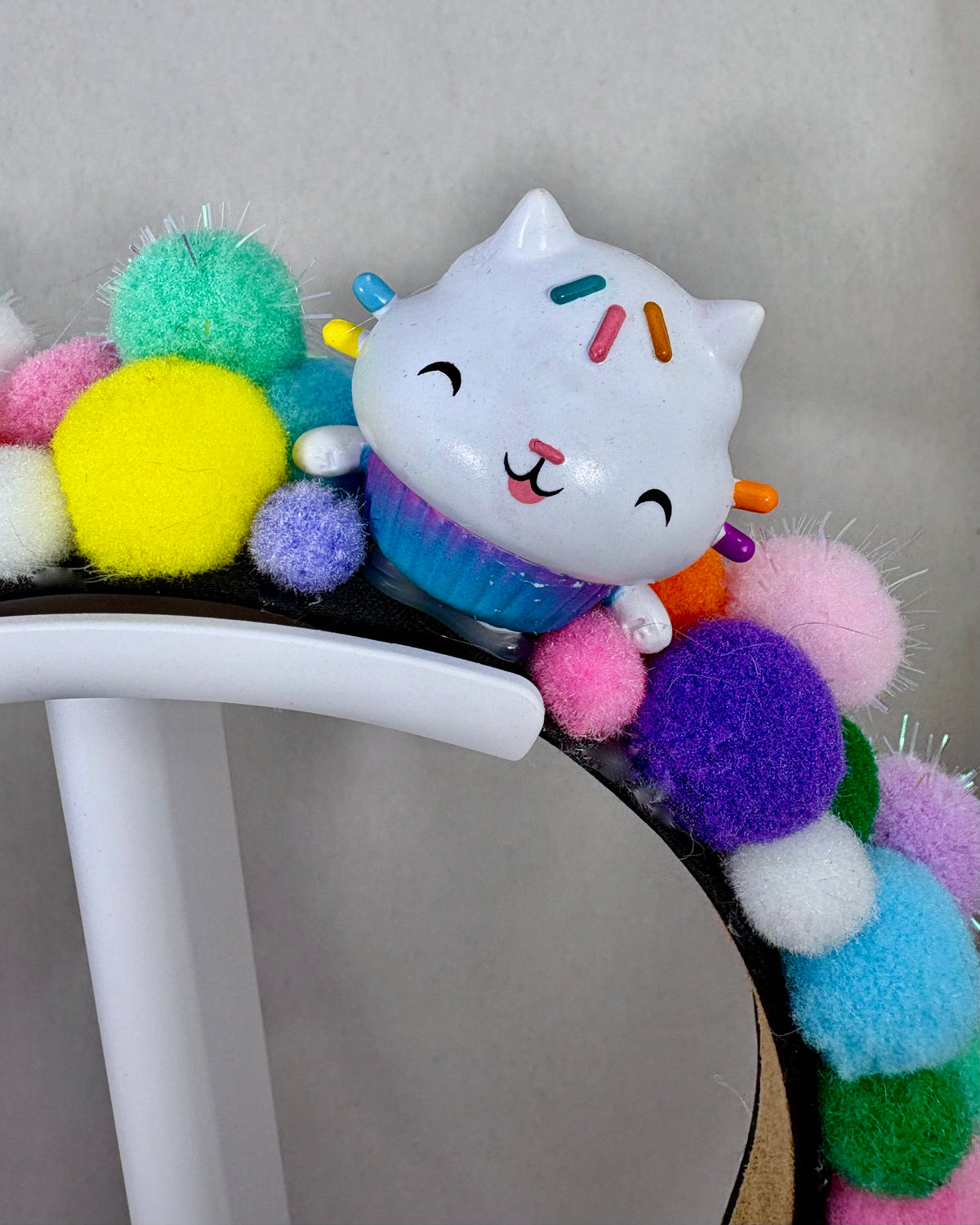 Close up of Colourful pom-pom headband with a cartoon cat character toy