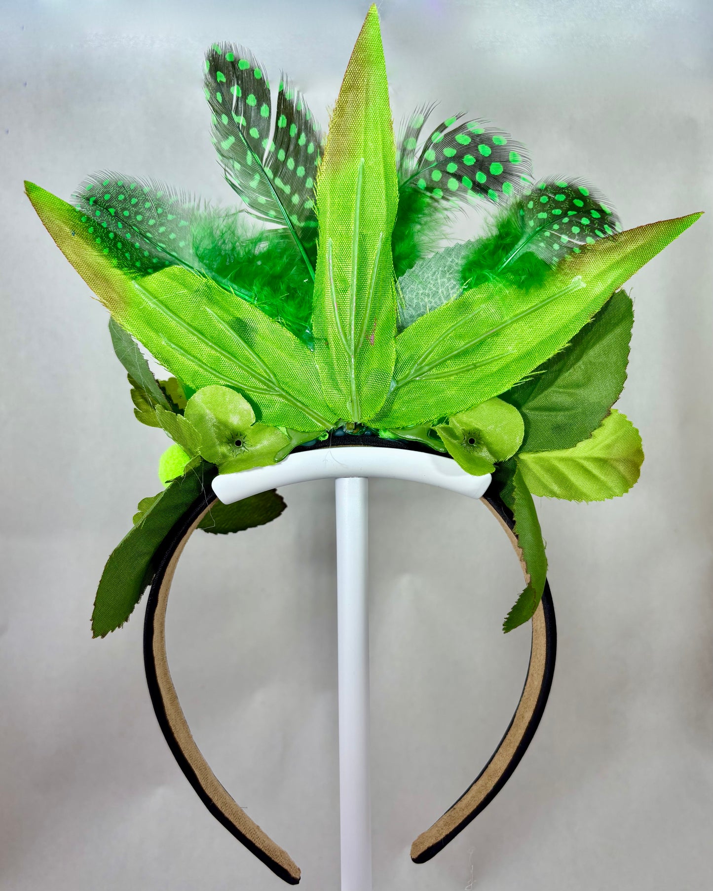 Back of a headband with green leaf and feather decorations