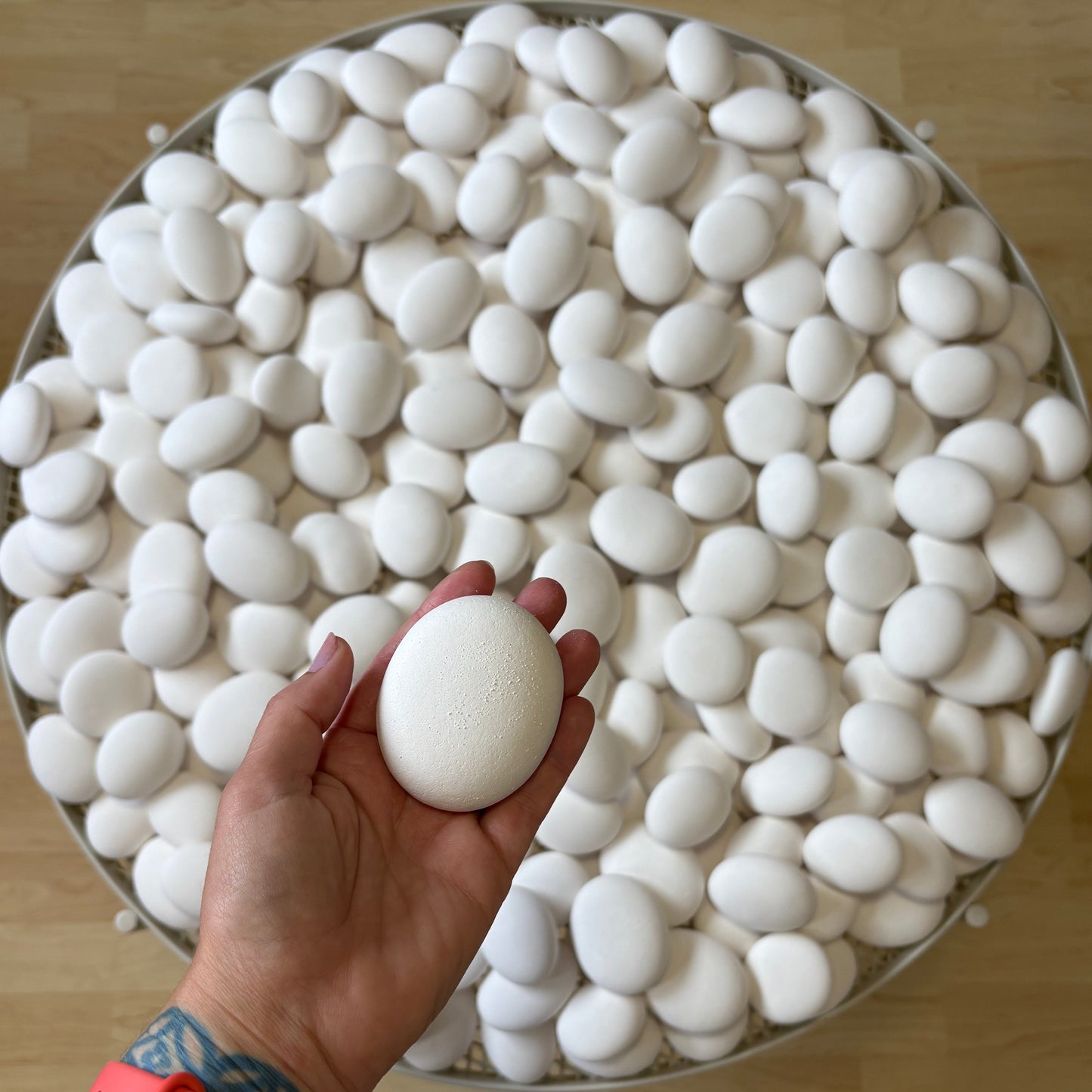 Hand holding a white stone over a large table full of white stones