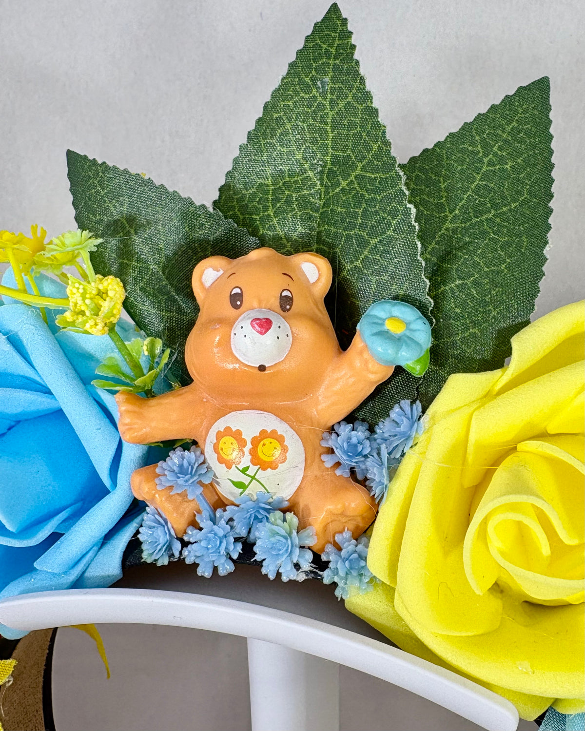 Close up of Decorative headband with yellow and blue flowers and an orange toy bear