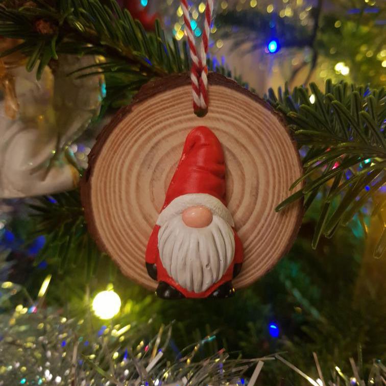 Mini Gonk painted up to look like a Santa, attached to a wood slice to make a Christmas Tree Ornament, hanging in a tree