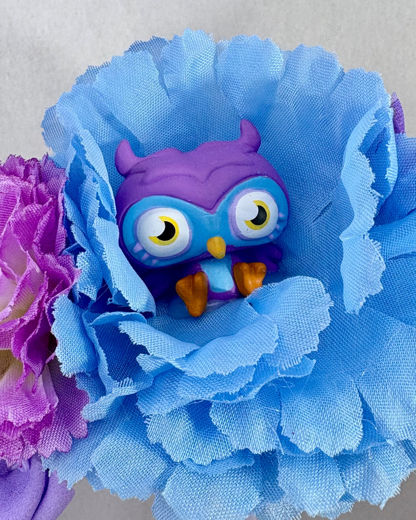 Close up of Headband with blue and purple flowers and a small owl figurine