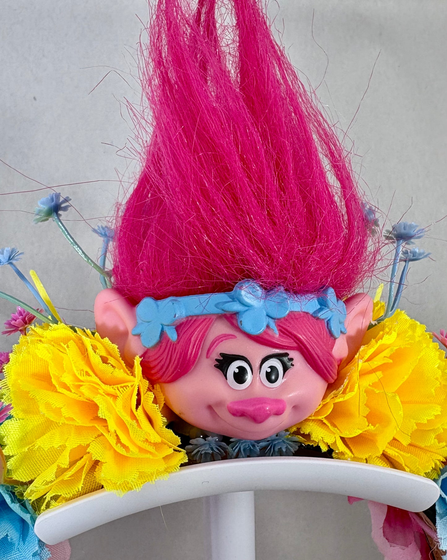 Colourful troll toy with pink hair and yellow flowers on a festival crown