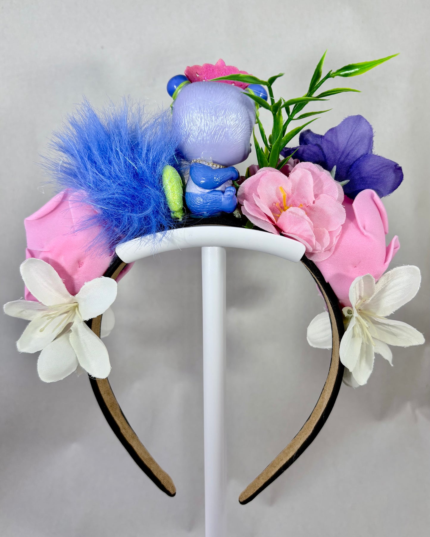 Back view of a colourful floral headband with a small purple panda toy figure