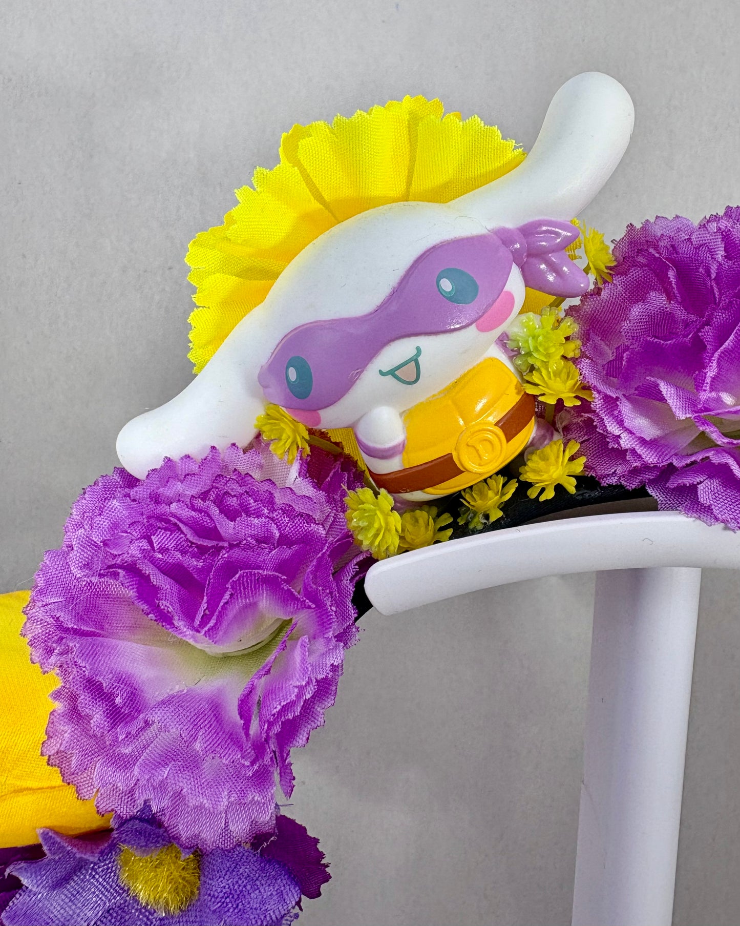 Close up of Floral headband with white puppy toy and purple and yellow flowers