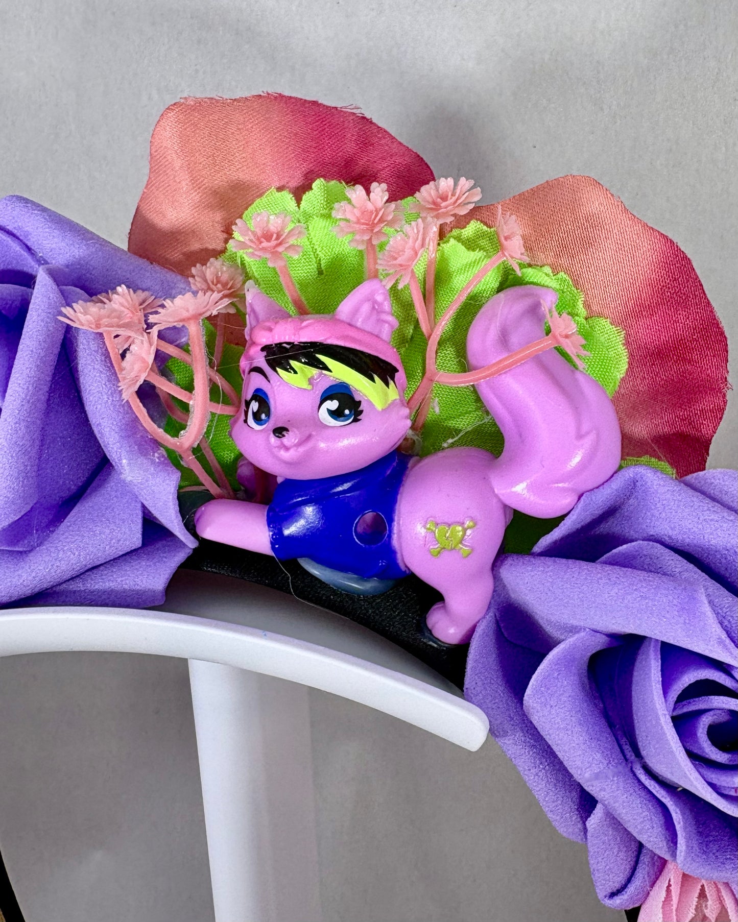 Close up of Headband with purple and pink flowers and a small pink toy cat