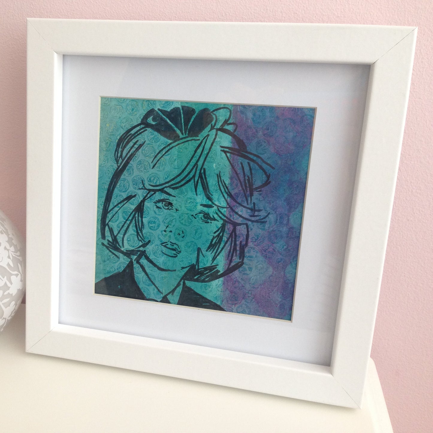 Framed turquoise and purple monoprint of a vintage inspired female character