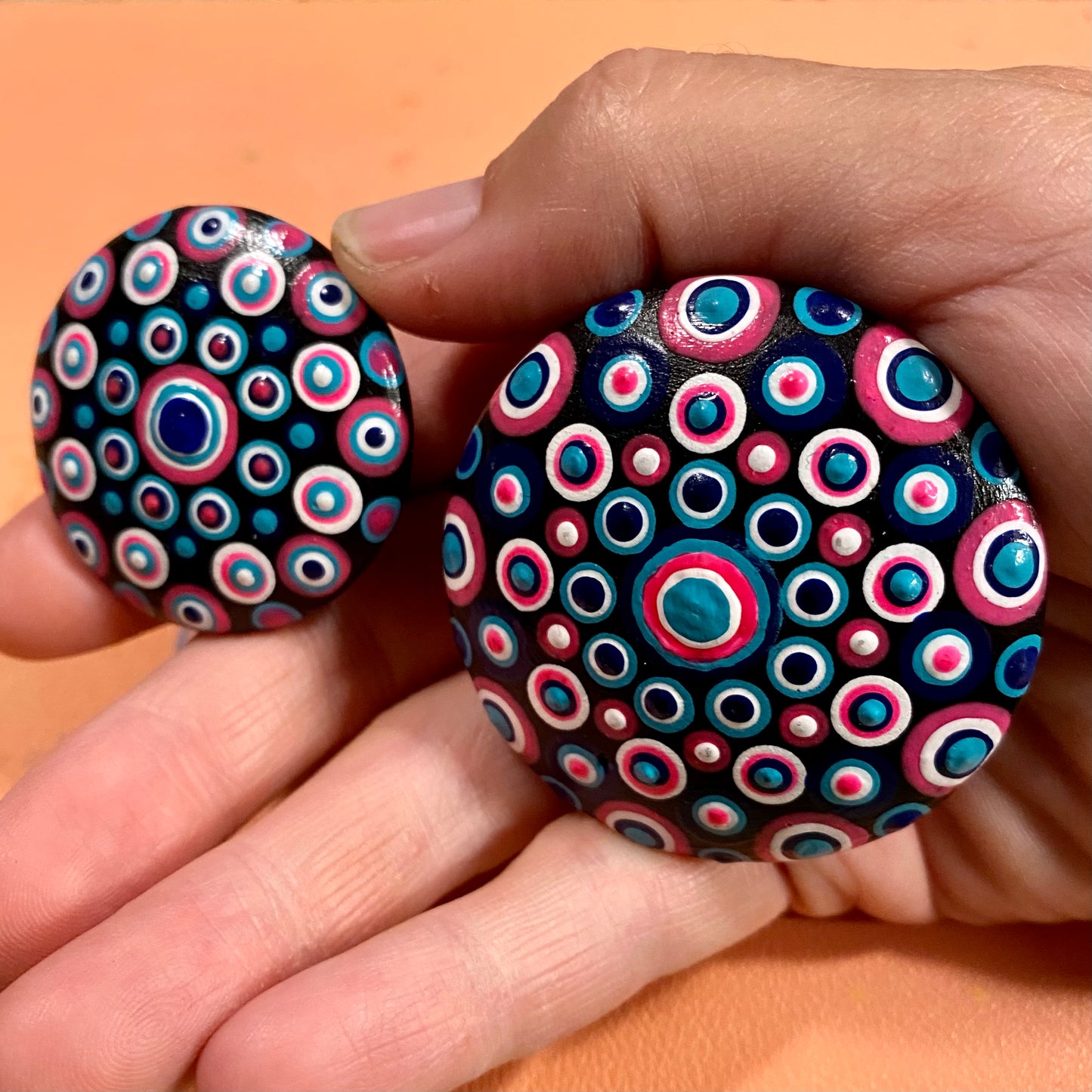 2 small mandala pebbles painted up to show how they can look.