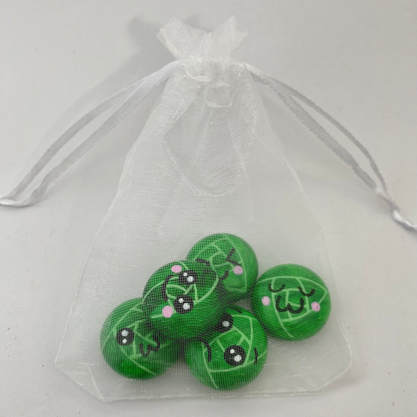 5 Hand painted tiny sprout pebbles each with a different cute faced expression in an organza bag
