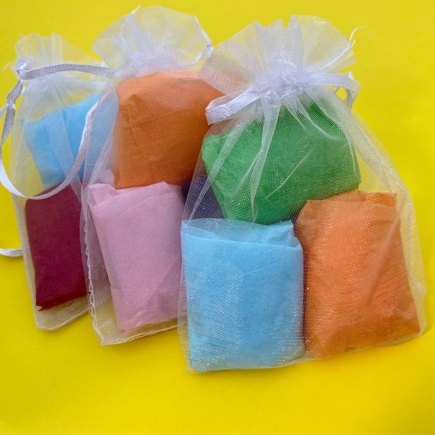 Sets of 3 pebbles wrapped in colourful tissue paper inside organza bags