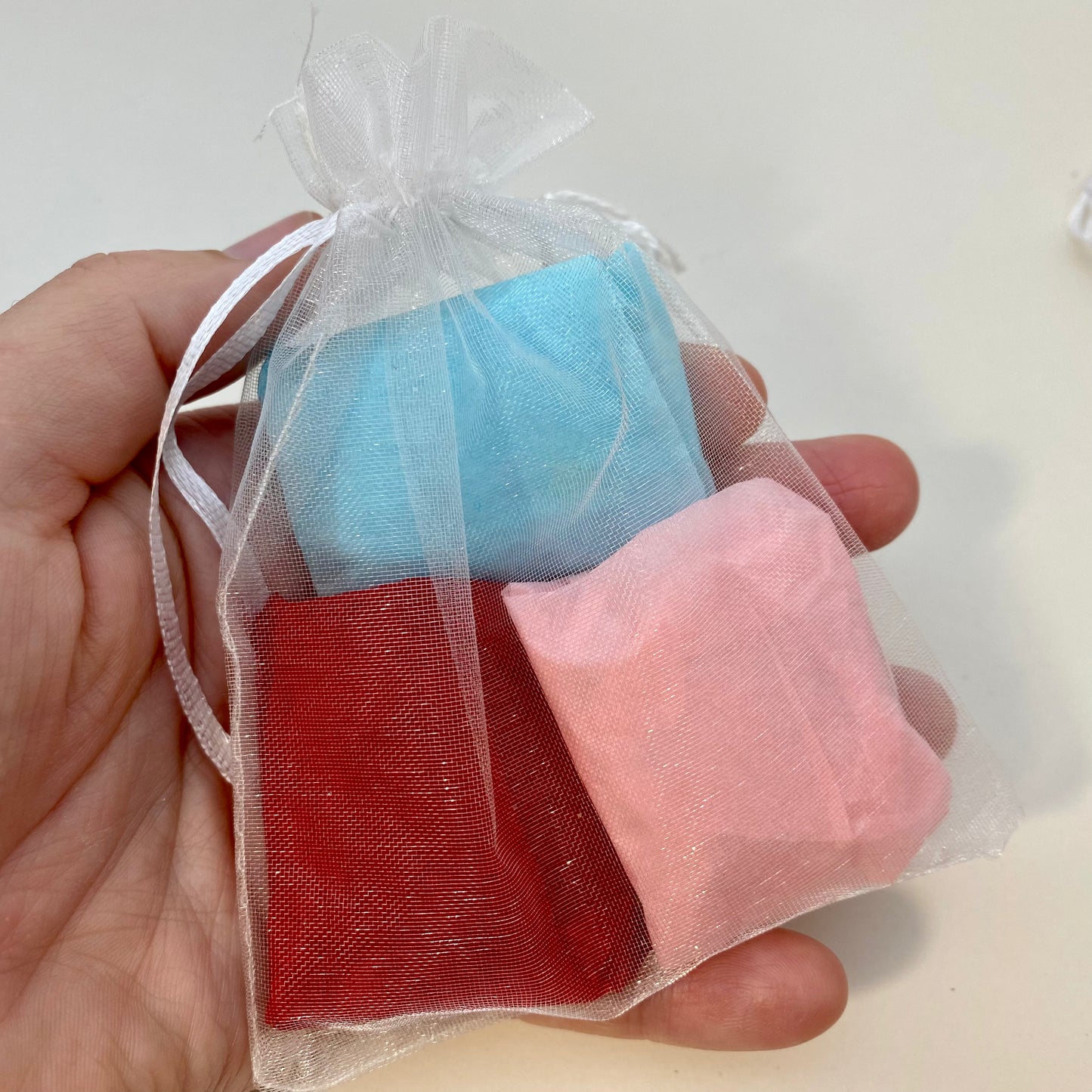 3 pebbles wrapped in colourful tissue paper inside an organza bag