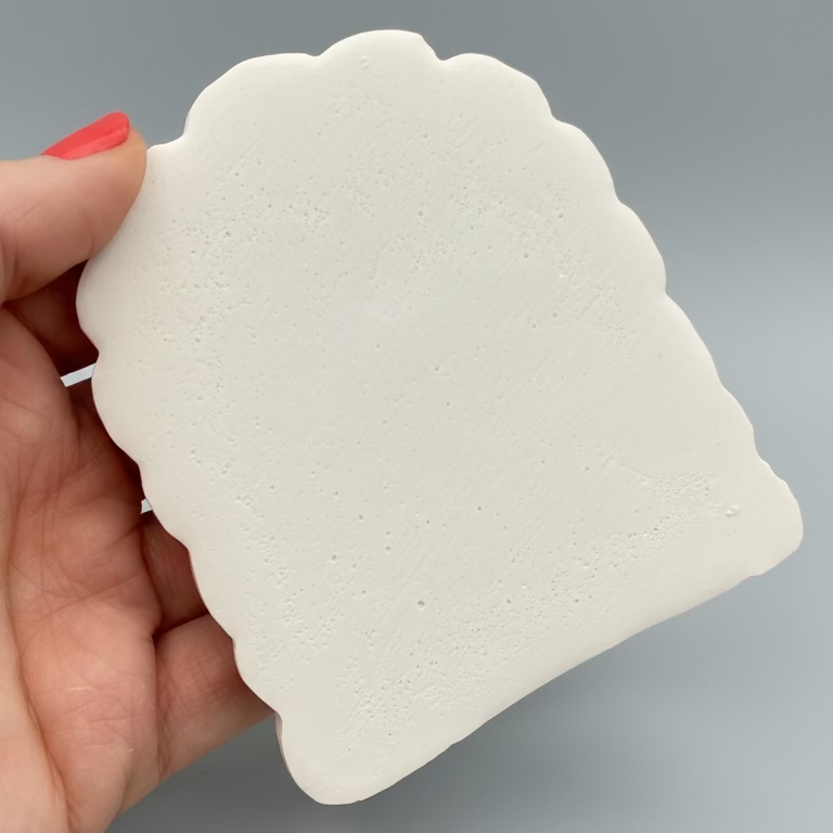 Hand holding a hand Cast Plaster Fairy Door ready to paint. Back view.