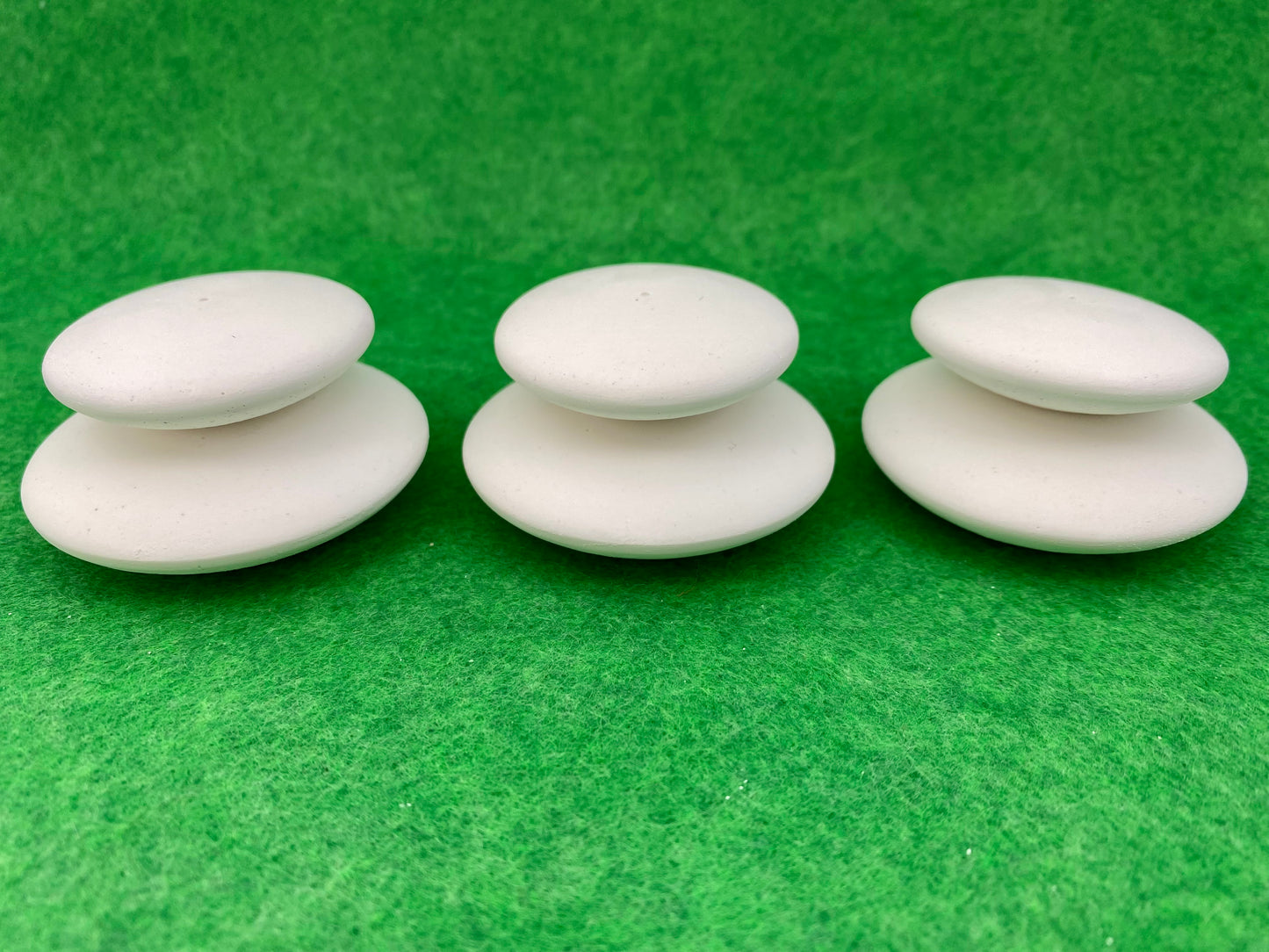 6 small white circular plaster pebbles in 2 sizes, stacked on top of each other