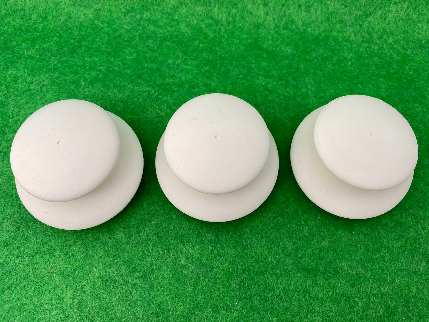 6 small white circular plaster pebbles in 2 sizes, stacked on top of each other