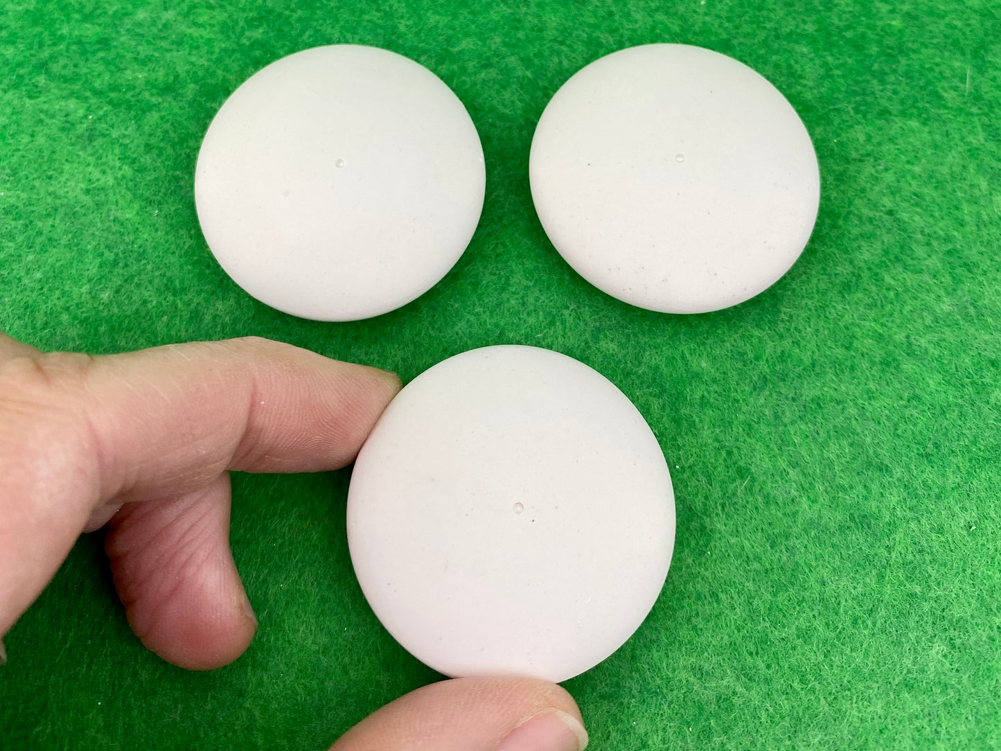 4cm white circular plaster pebbles, each with a tiny centre hole to help with painting mandalas. Photographed with a hand