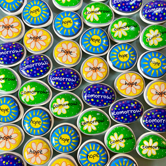 Lots of Yellow, Green, and Blue Hand painted pebbles with the words Hope and Tomorrow written on