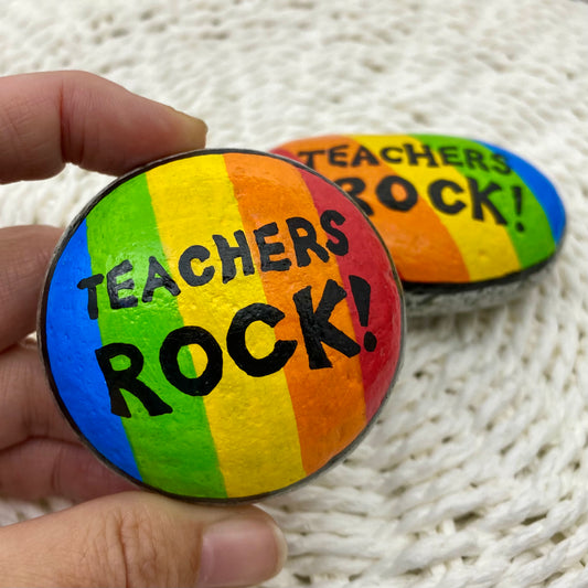 2 rocks painted with bright rainbow stripes and the words"Teachers Rock" written on.
