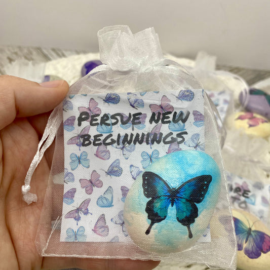 Blue butterfly decal on a marbled pebble with an affirmation card reading "Pursue new beginnings" in an organza bag