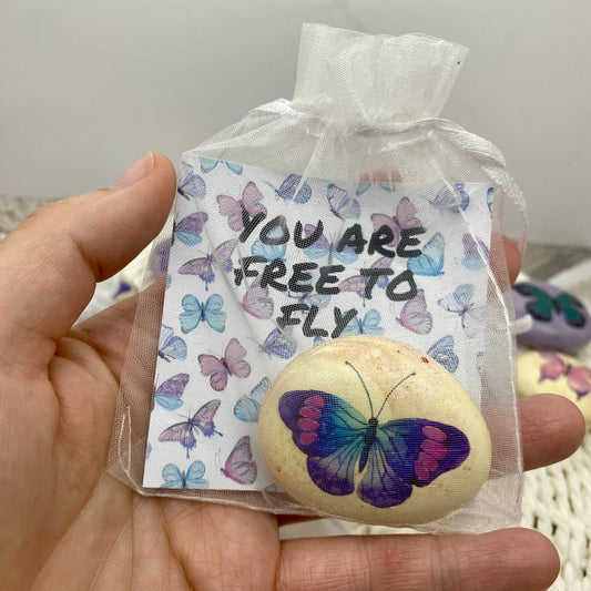Purple butterfly decal on a marbled pebble with an affirmation card reading "You are free to fly" in an organza bag