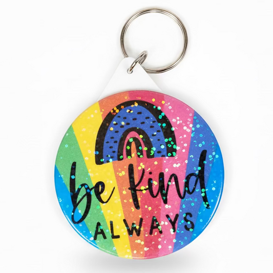 A photo of a sparkly keyring with a rainbow background and the text Be Kind Always written on