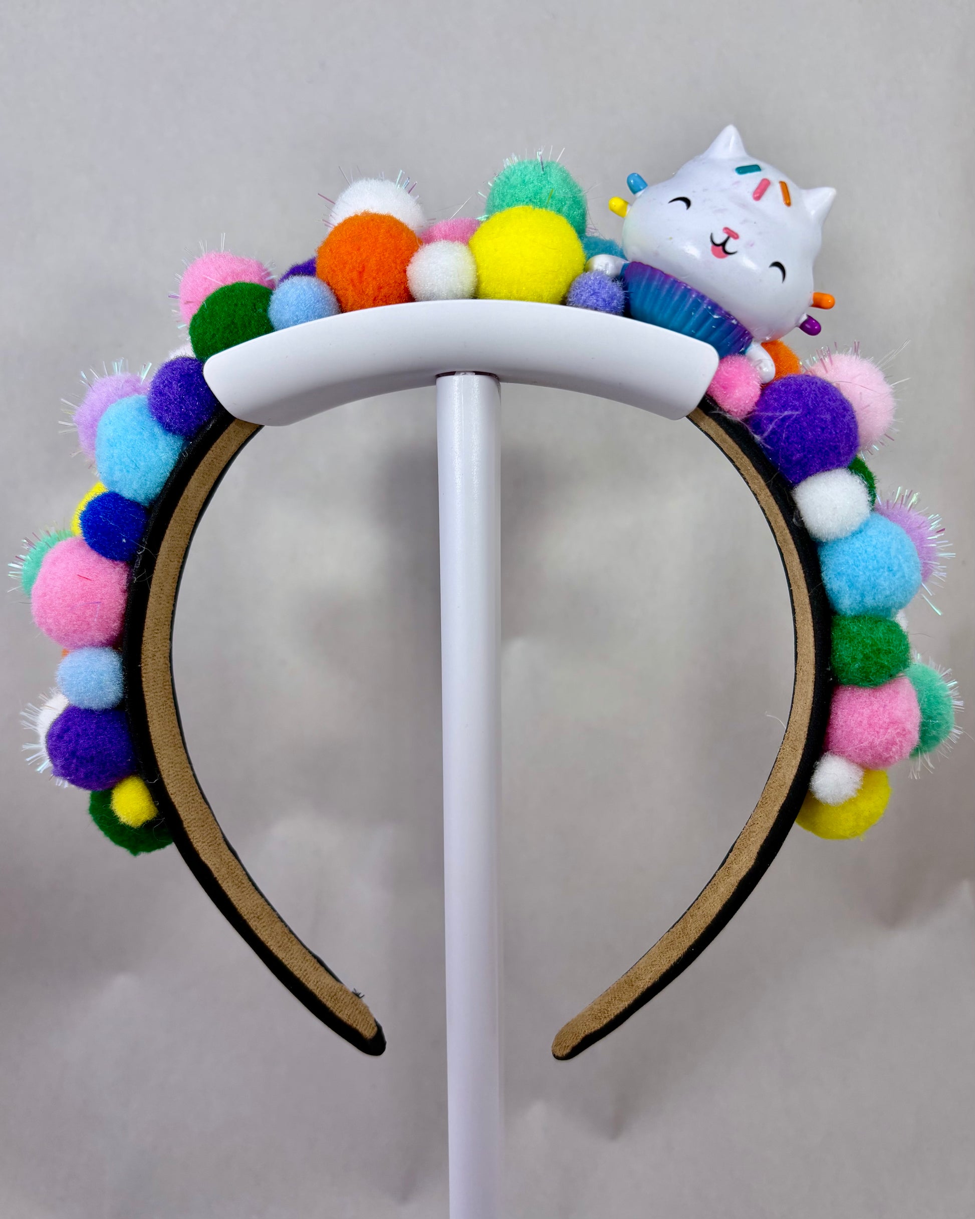 Colourful pom-pom headband with a cartoon cat character toy