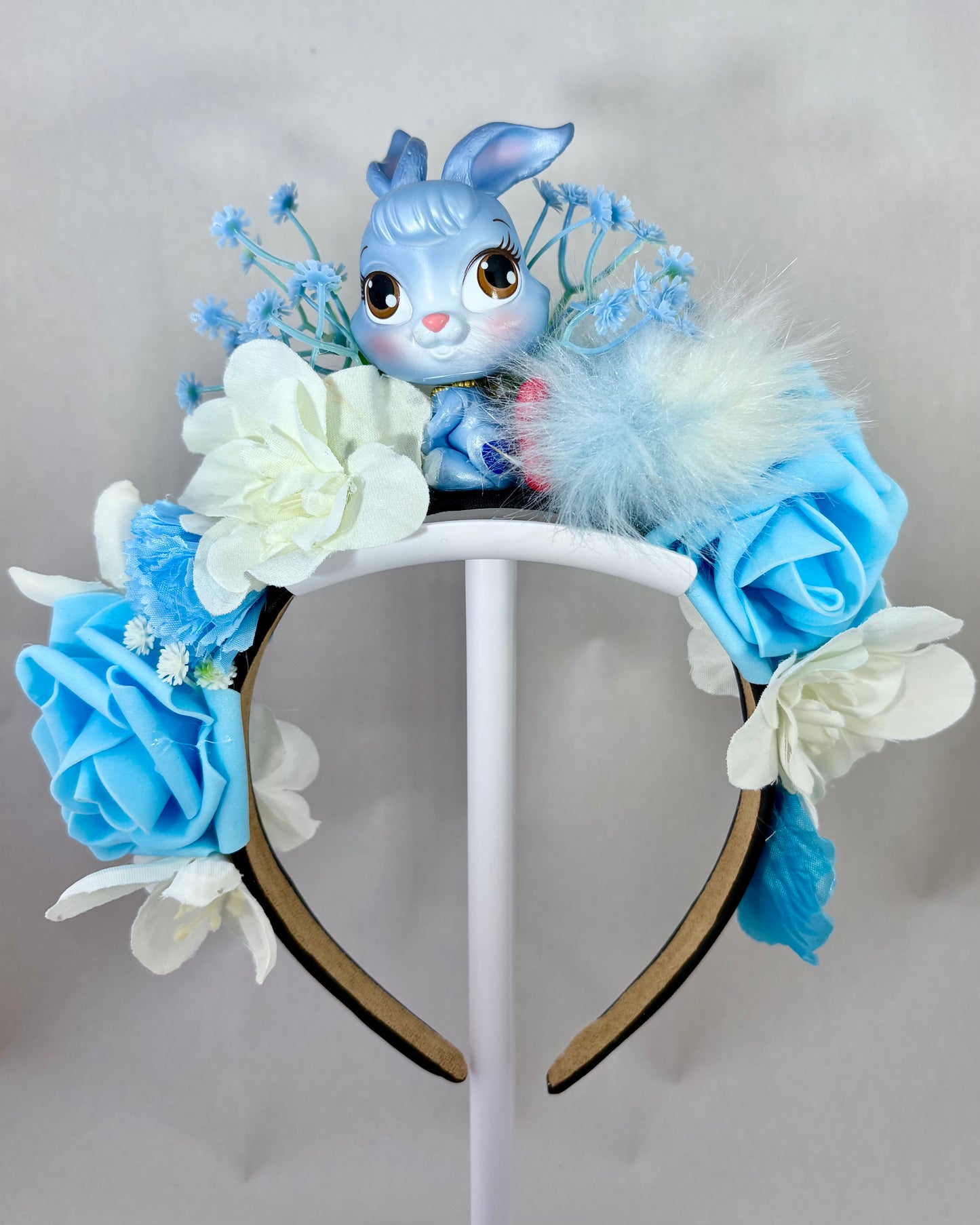 Decorative headband with blue and white flowers and a blue rabbit toy in the centre