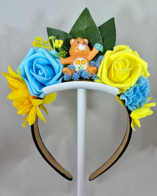 Decorative headband with yellow and blue flowers and an orange toy bear