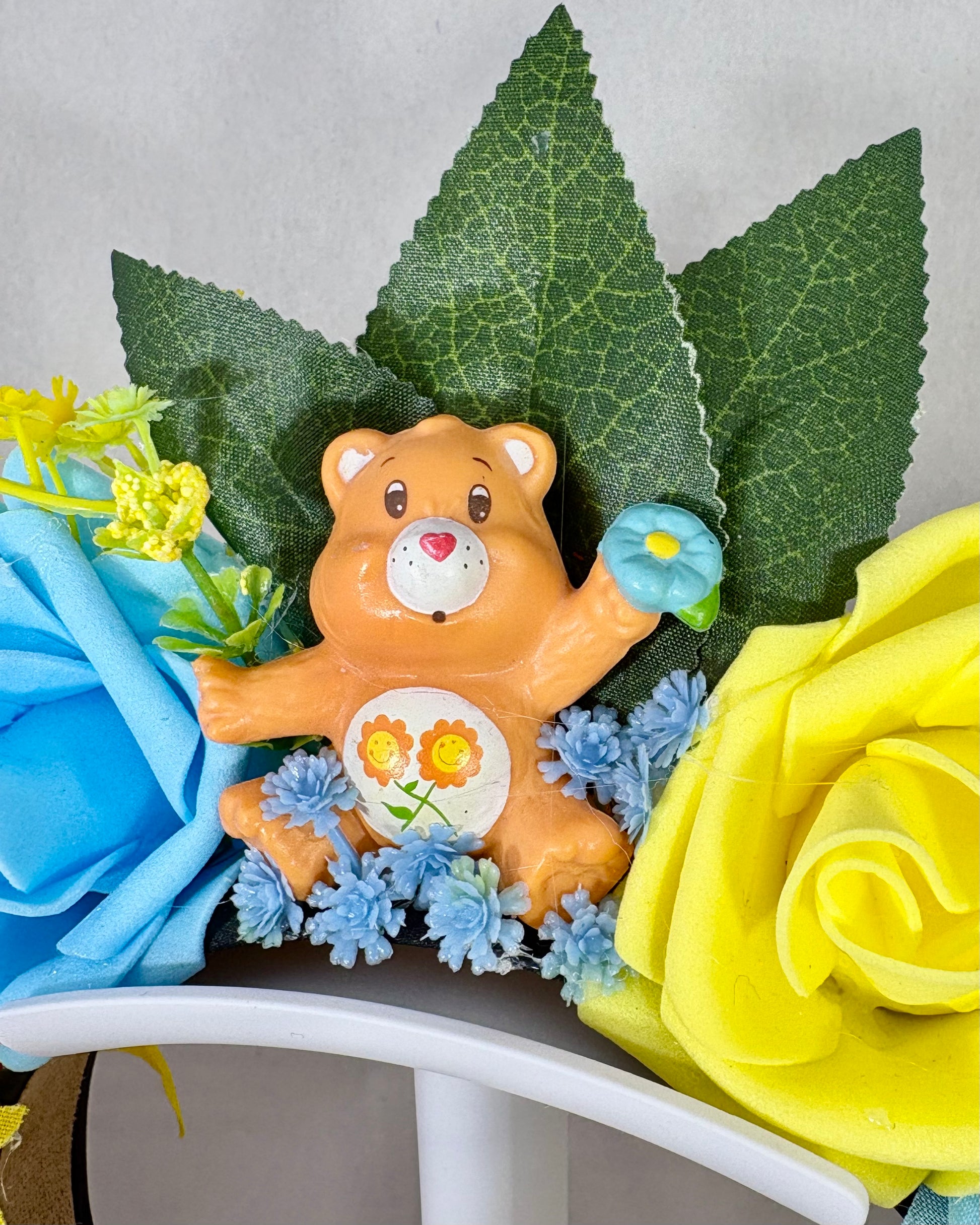 Close up of Decorative headband with yellow and blue flowers and an orange toy bear