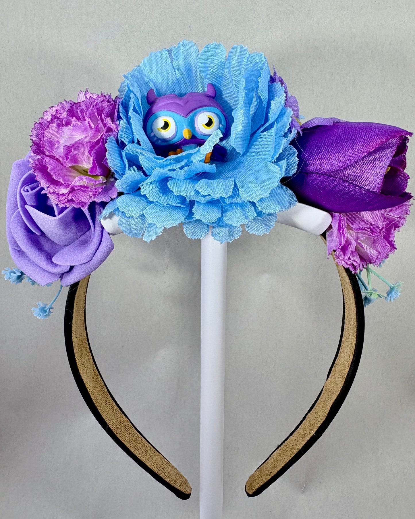 Headband with blue and purple flowers and a small owl figurine 