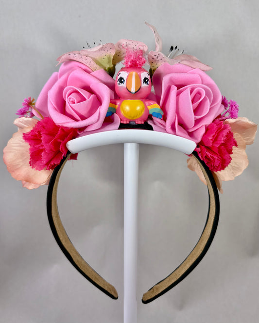 Headband with pink flowers and a small toy bird figurine