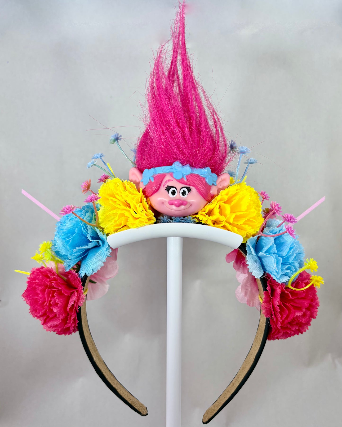 Colourful headband with flowers and a pink troll toy in the centre