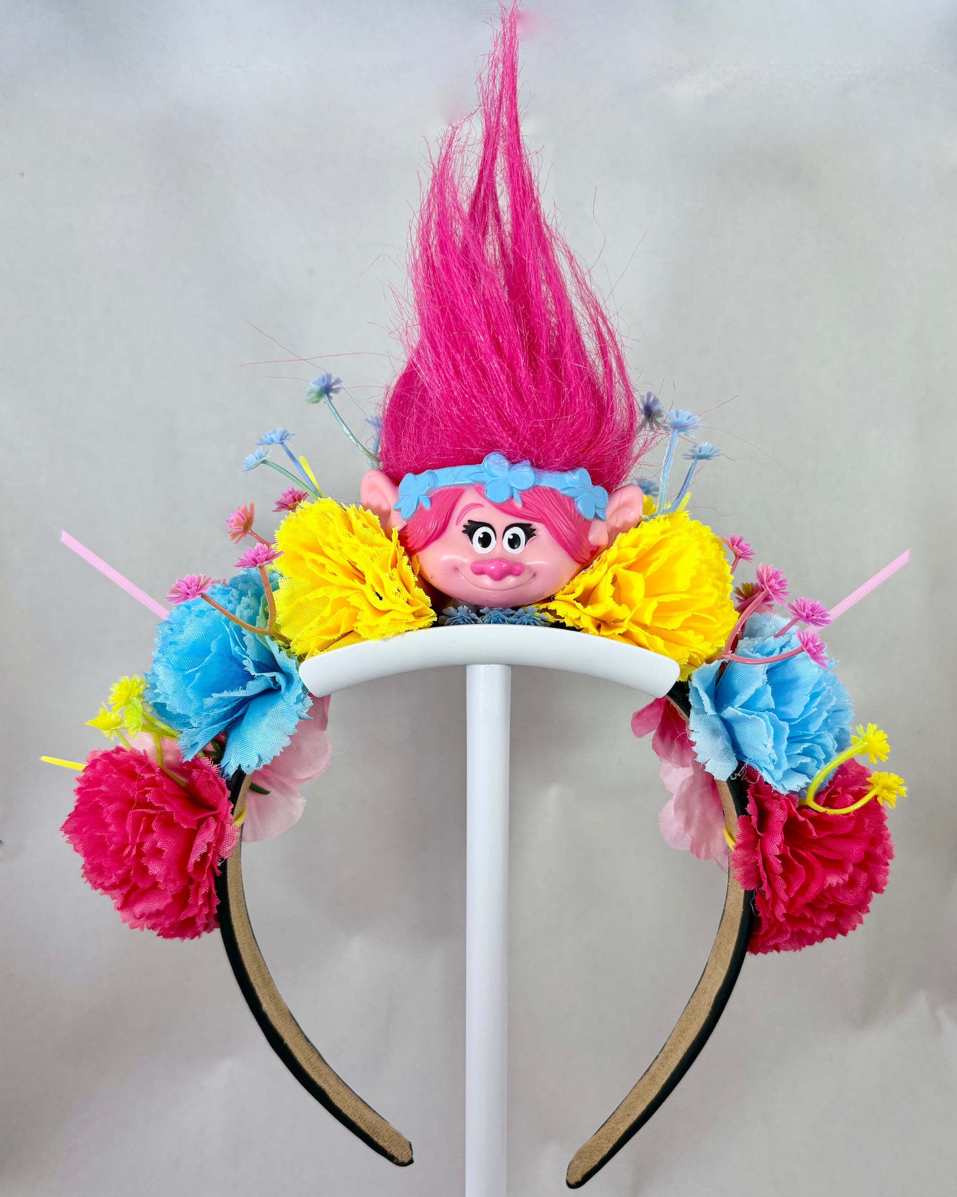 Colourful headband with flowers and a pink troll toy in the centre