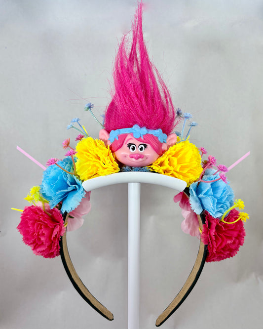 Colourful headband with flowers and a pink troll toy in the centre
