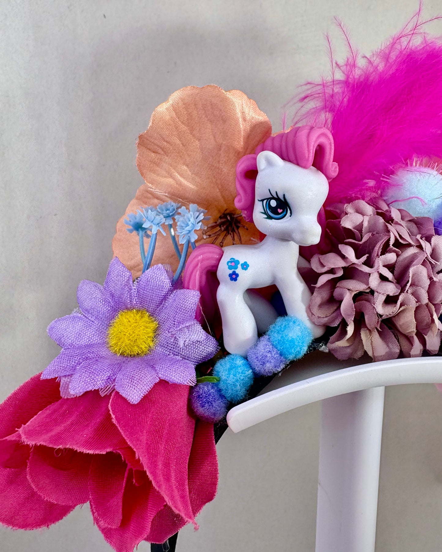 Close up of Colourful headband with flowers and a small pony figurine