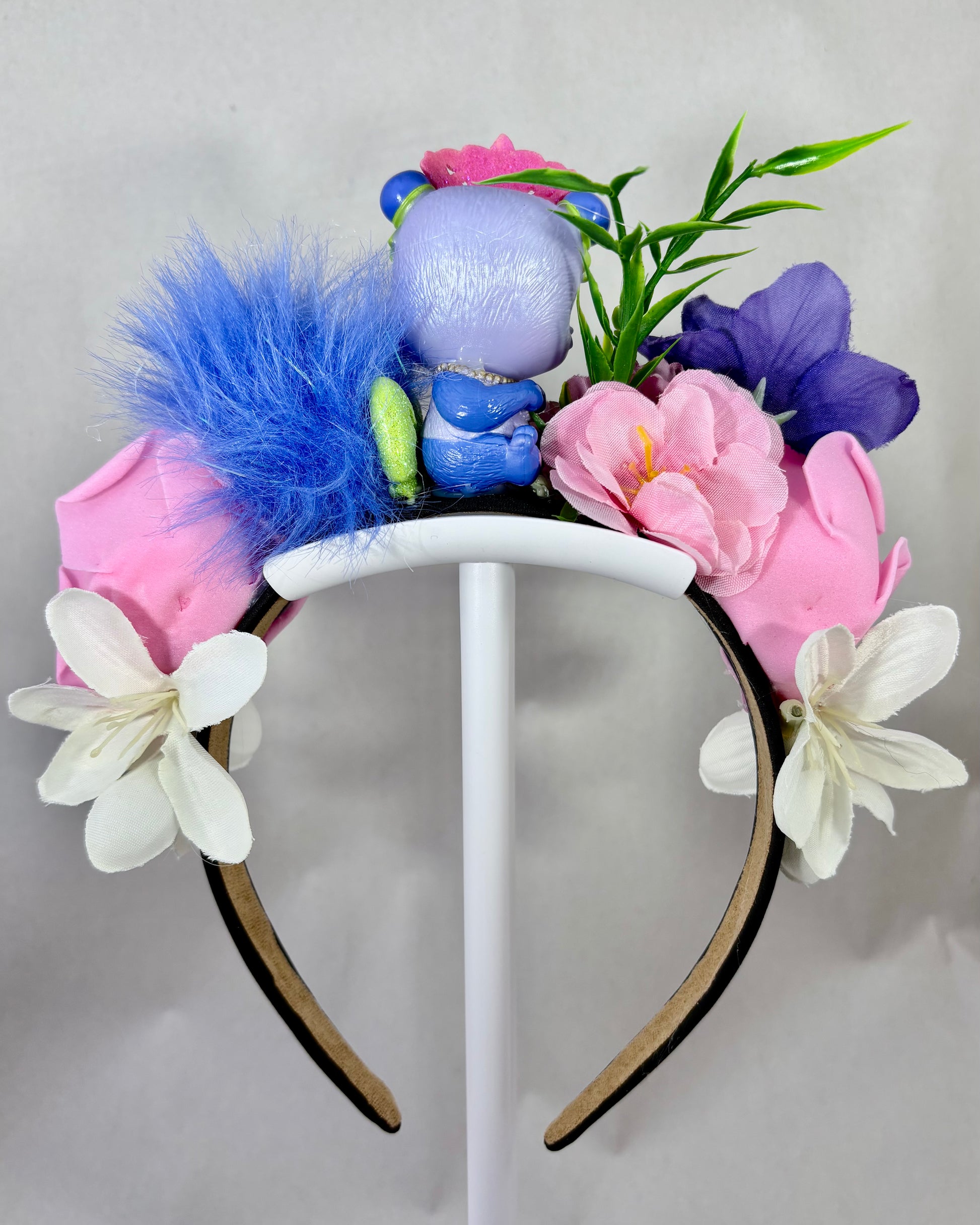 Back view of a colourful floral headband with a small purple panda toy figure