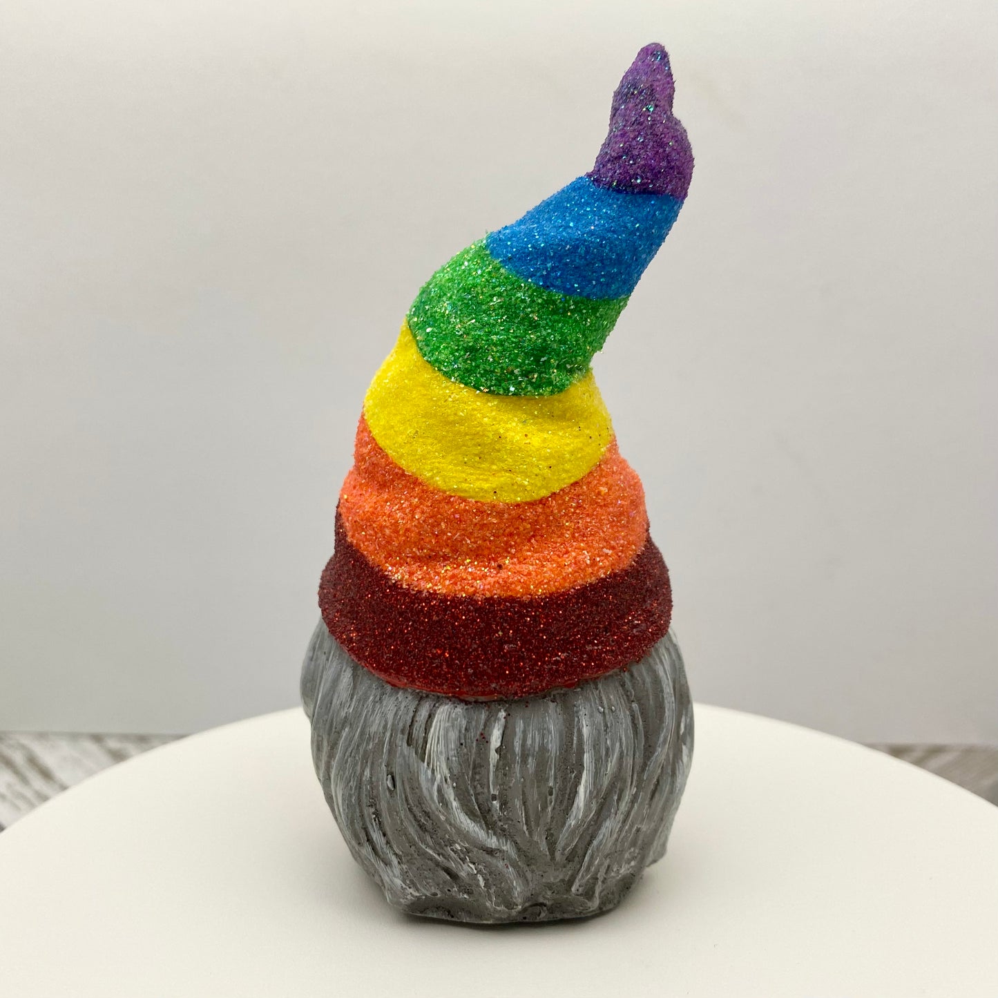 Small hand painted gonk statue with a Glittery Rainbow hat and grey beard. Back view.