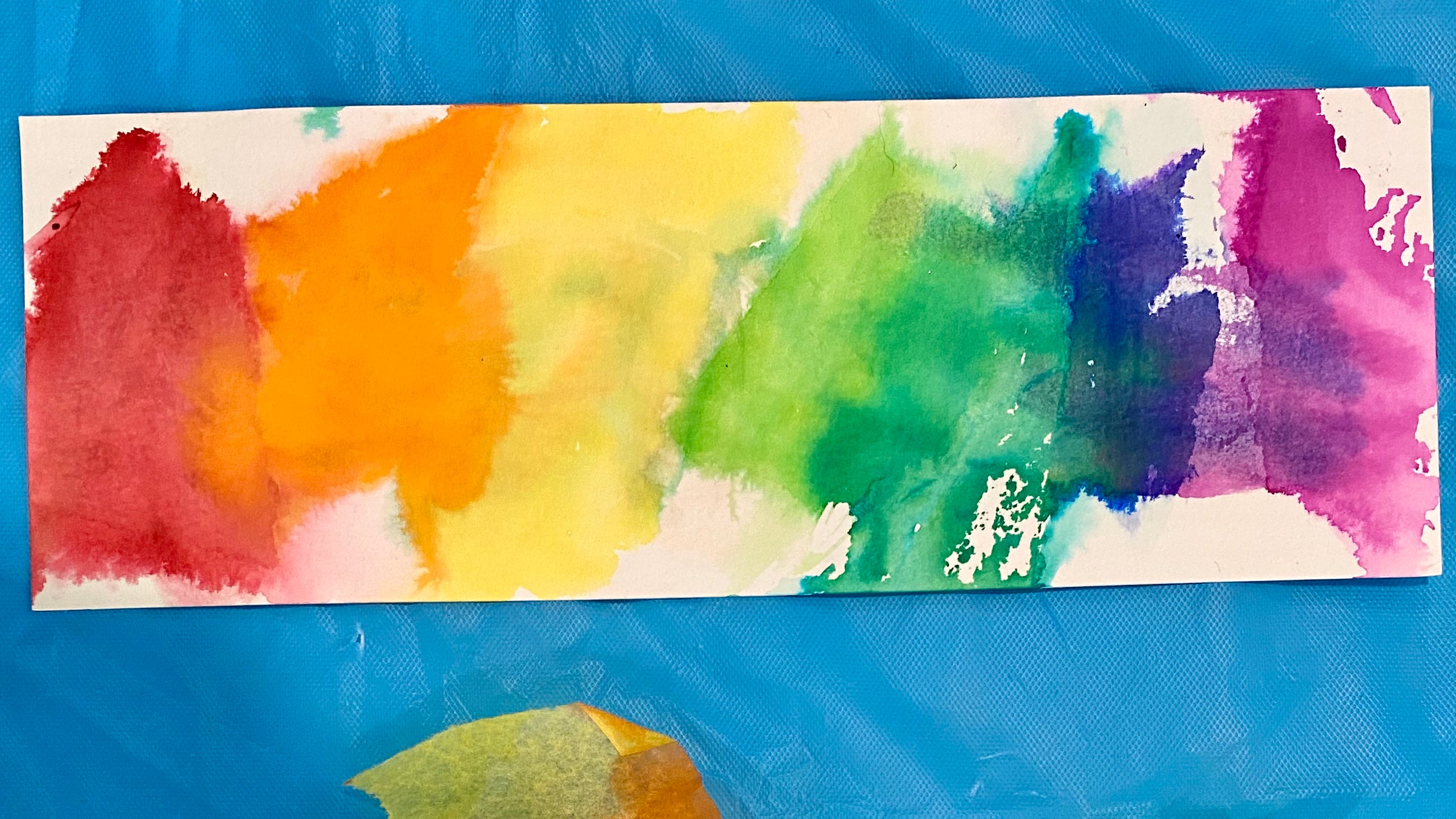 A rainbow bookmark made from bleeding tissue papers onto card
