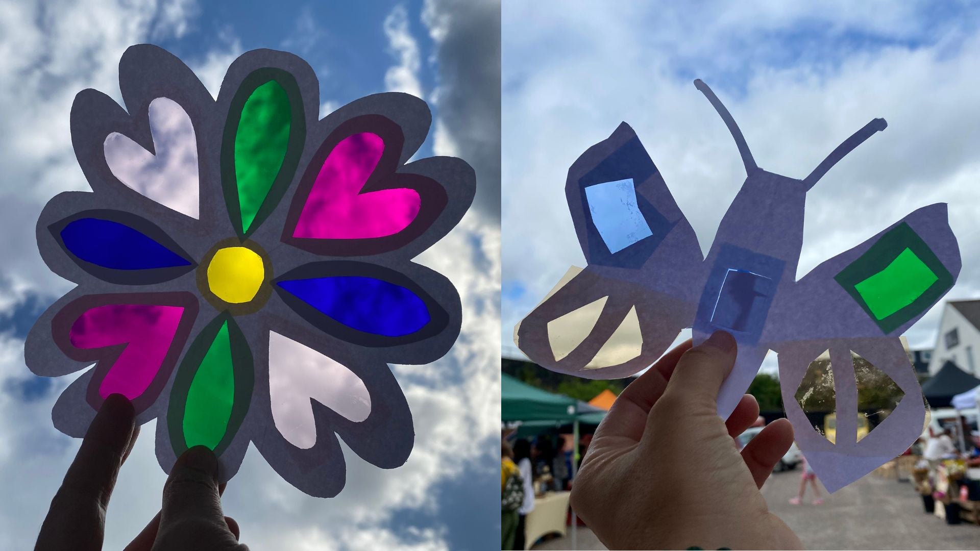 2 paper and coloured acetate handmade suncatchers being held up against the sky, the sun is shining through the acetate. One is a flower with heart shaped petals and the other is a butterfly. There are market stalls in the background.