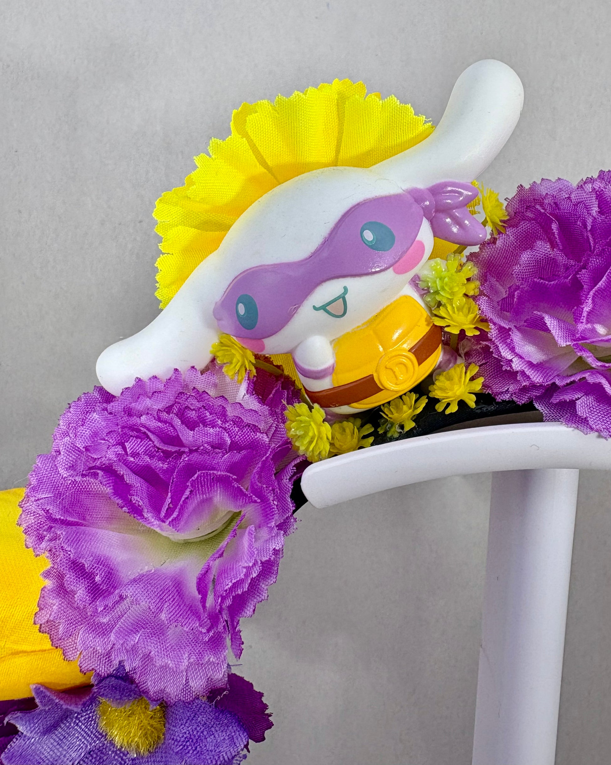 Close up of Floral headband with white puppy toy and purple and yellow flowers