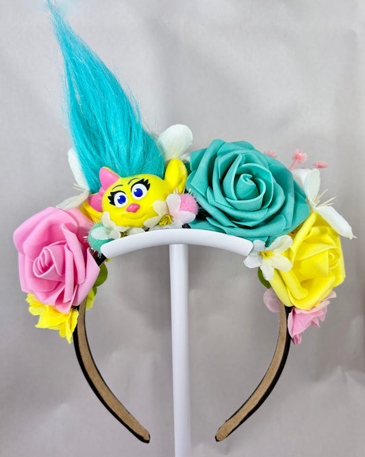 Colourful Festival Crown with pink, yellow and teal flowers and a troll toy