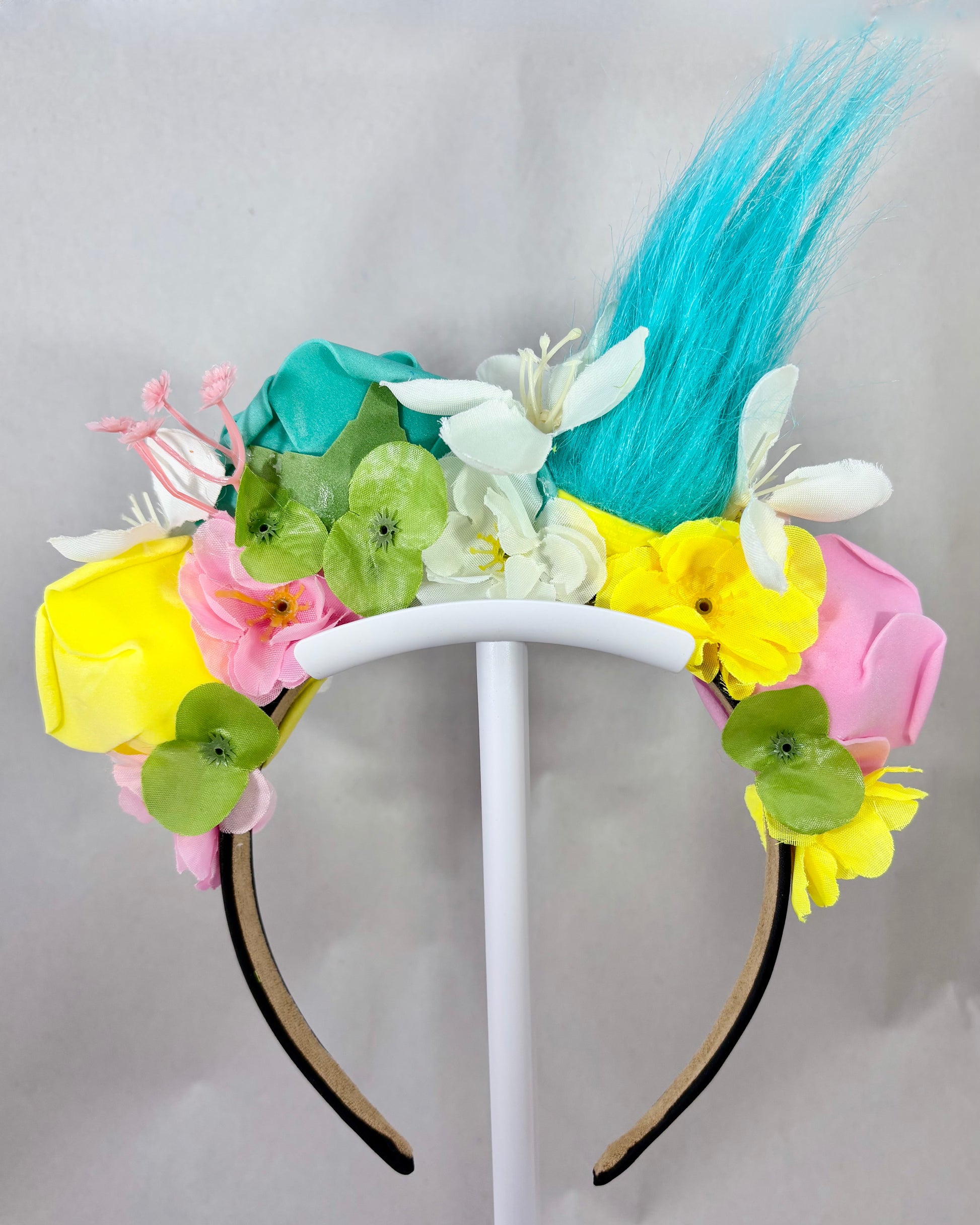 Back of Colourful Festival Crown with pink, yellow and teal flowers and a troll toy