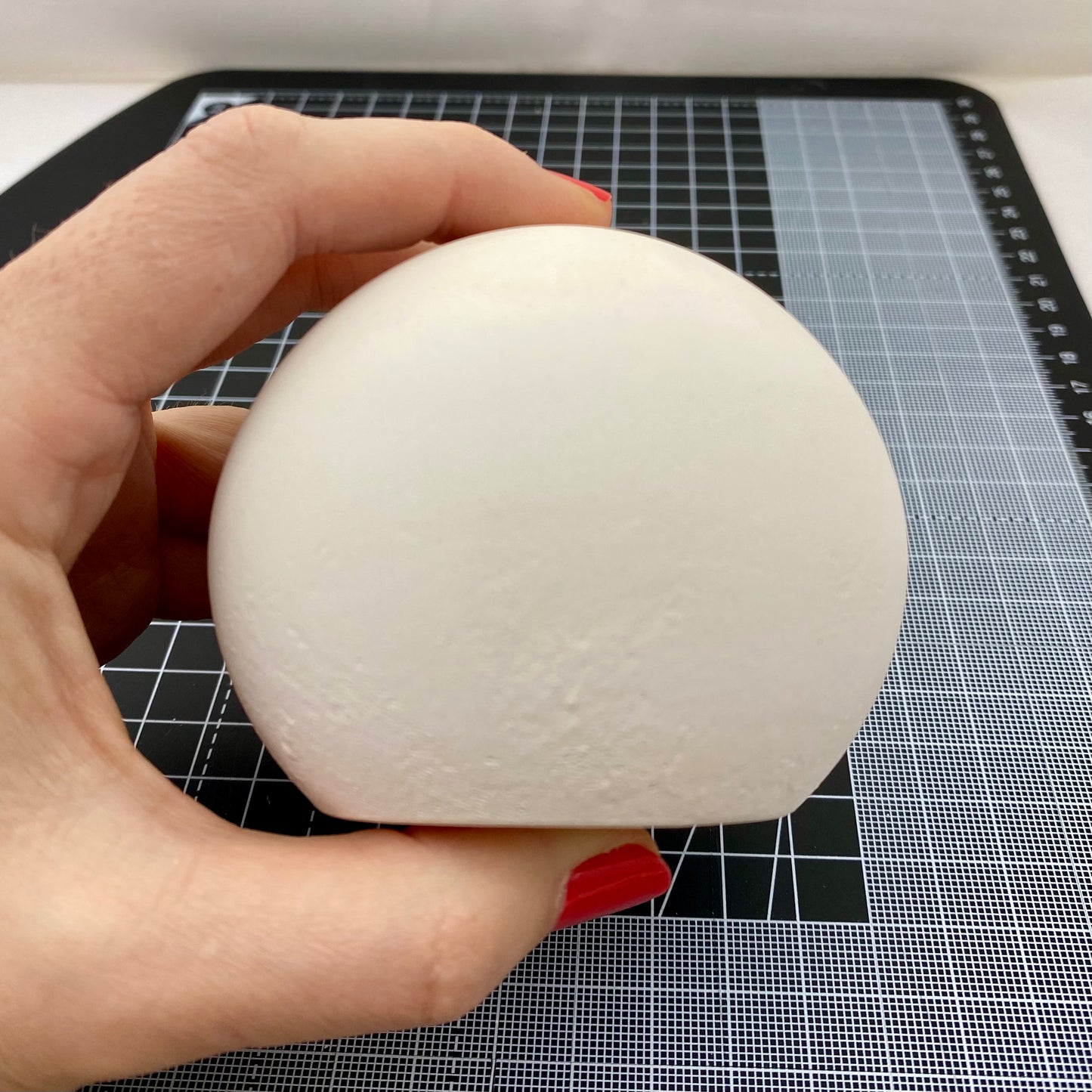 Hand cast Plaster Sphere Paperweight for Mandala painting. Held to show size. Side view.