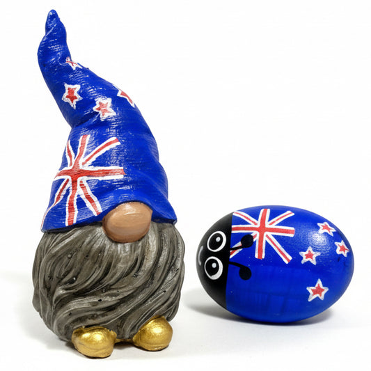 A small hand painted gonk statue with an Australian Flag hat, grey beard and gold shoes. Next to him a small rock bug painted with an Australian flag and cute eyes.
