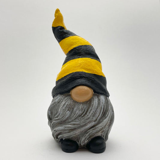 A small hand painted gonk statue one with a Yellow and Black Striped Bee Hat, a Grey Beard and Black Shoes. Front view.