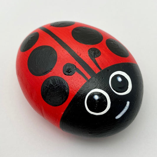A Smooth Hand painted Red and Black Ladybug Pebble with a cute face with big painted eyes.
