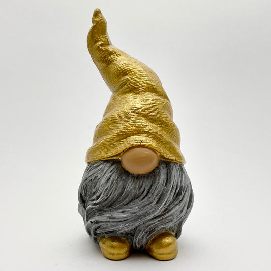 A small hand painted gonk statue with a gold hat and matching shoes and a grey beard. 