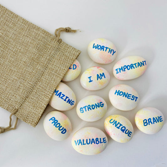 A hessian bag with hand painted affirmation pebbles spilling out