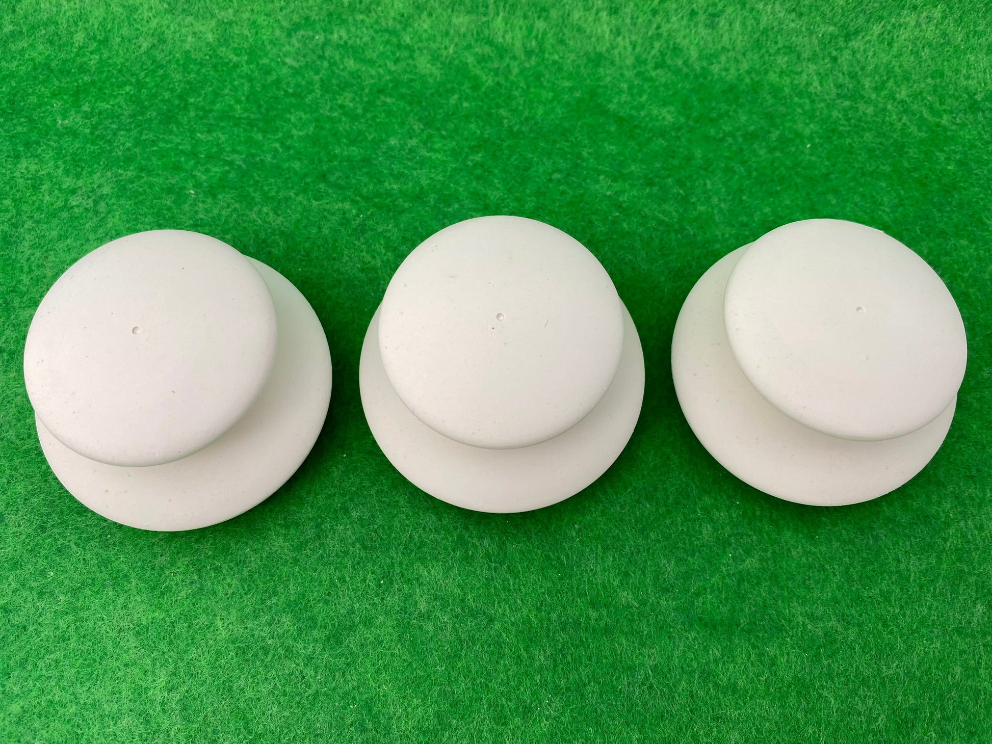 6 small white circular plaster pebbles in 2 sizes, stacked on top of each other