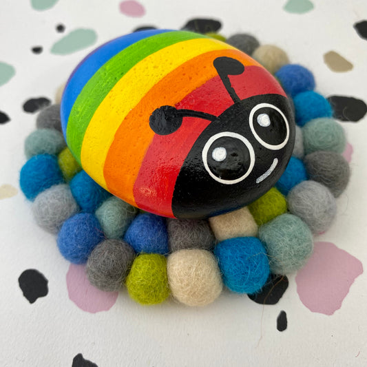 Hand painted Rainbow Bug Pebble on Blue Felt Mat