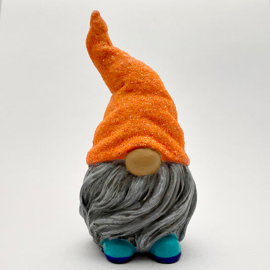 A small hand painted gonk statue with a Glittery orange hat, grey beard and blue shoes. 